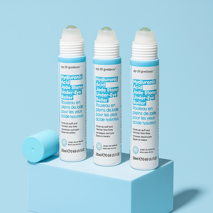 Slim turquoise tube of Masque BAR my iN.gredients Hyaluronic Acid Jade Stone Under-Eye Roller with jade tip exposed on a blue background, a cooling vegan treatment that hydrates, brightens dark circles and softens fine lines under the eyes.