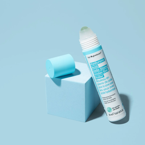 Slim turquoise tube of Masque BAR my iN.gredients Hyaluronic Acid Jade Stone Under-Eye Roller with jade tip exposed on a blue background, a cooling vegan treatment that hydrates, brightens dark circles and softens fine lines under the eyes.