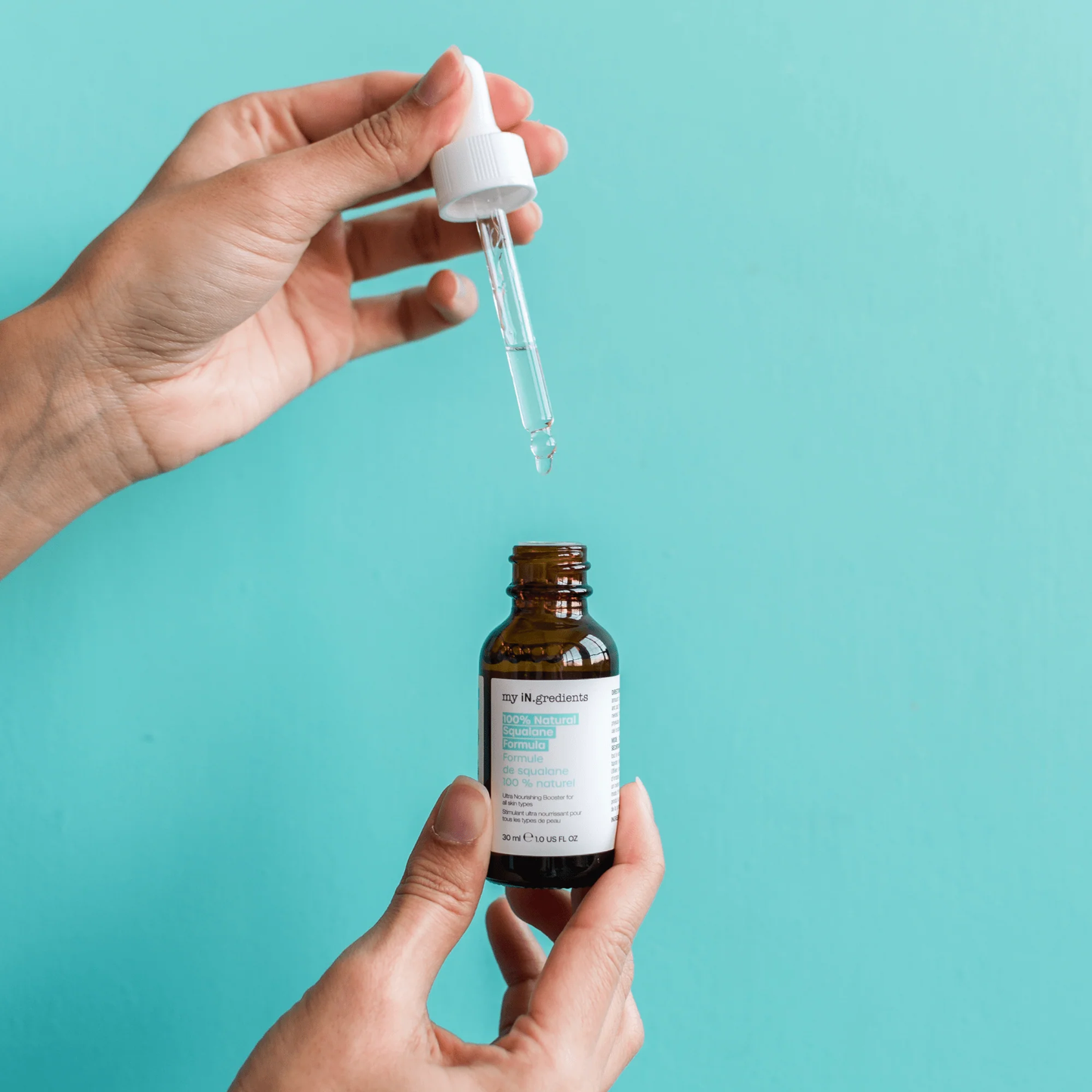 Amber glass bottle of my iN.gredients 100% Natural Squalane Formula 30ml with white dropper and turquoise label on rippling water background, highlighting a lightweight vegan oil that seals in moisture and soothes dry, red skin.