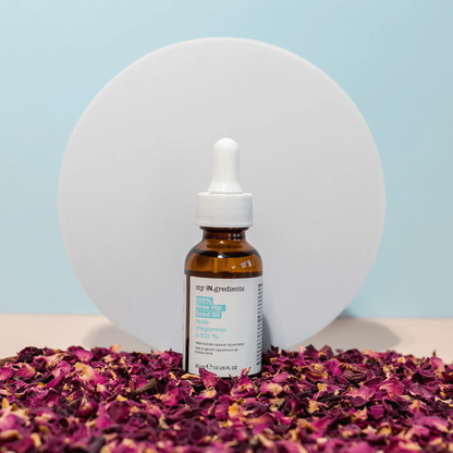 Amber glass bottle of my iN.gredients 100% Rose Hip Seed Oil 30ml with white dropper and minimal turquoise label, shown against a soft blue background, highlighting its pure, vegan formula for hydrating and soothing dull, dry, itchy facial skin.
